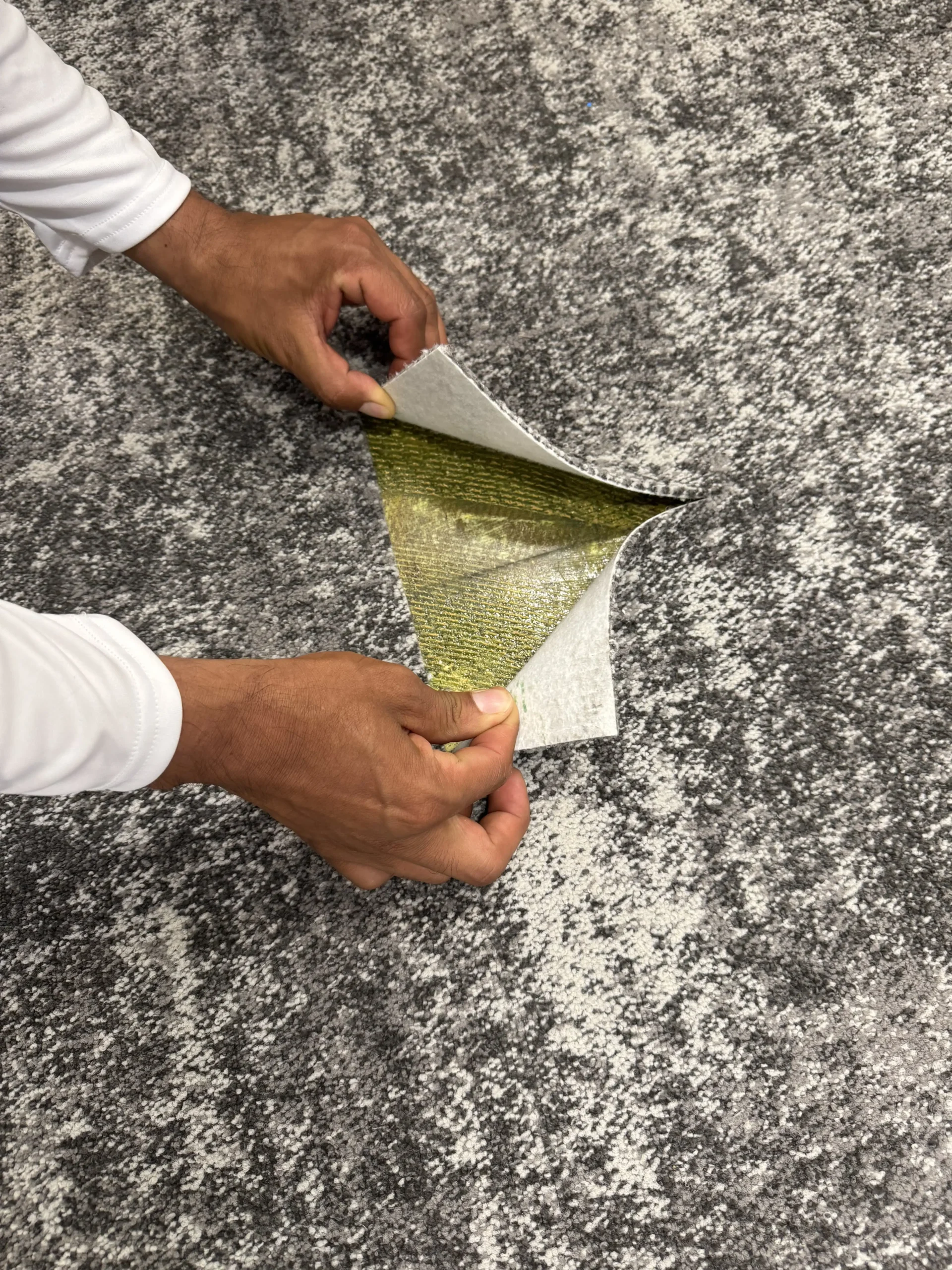 Professional installers laying down a rustic wood-look sheet vinyl floor roll in a commercial office lobby.