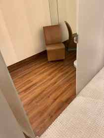 Finished wood-look luxury vinyl plank with a tan chair in a commercial space.