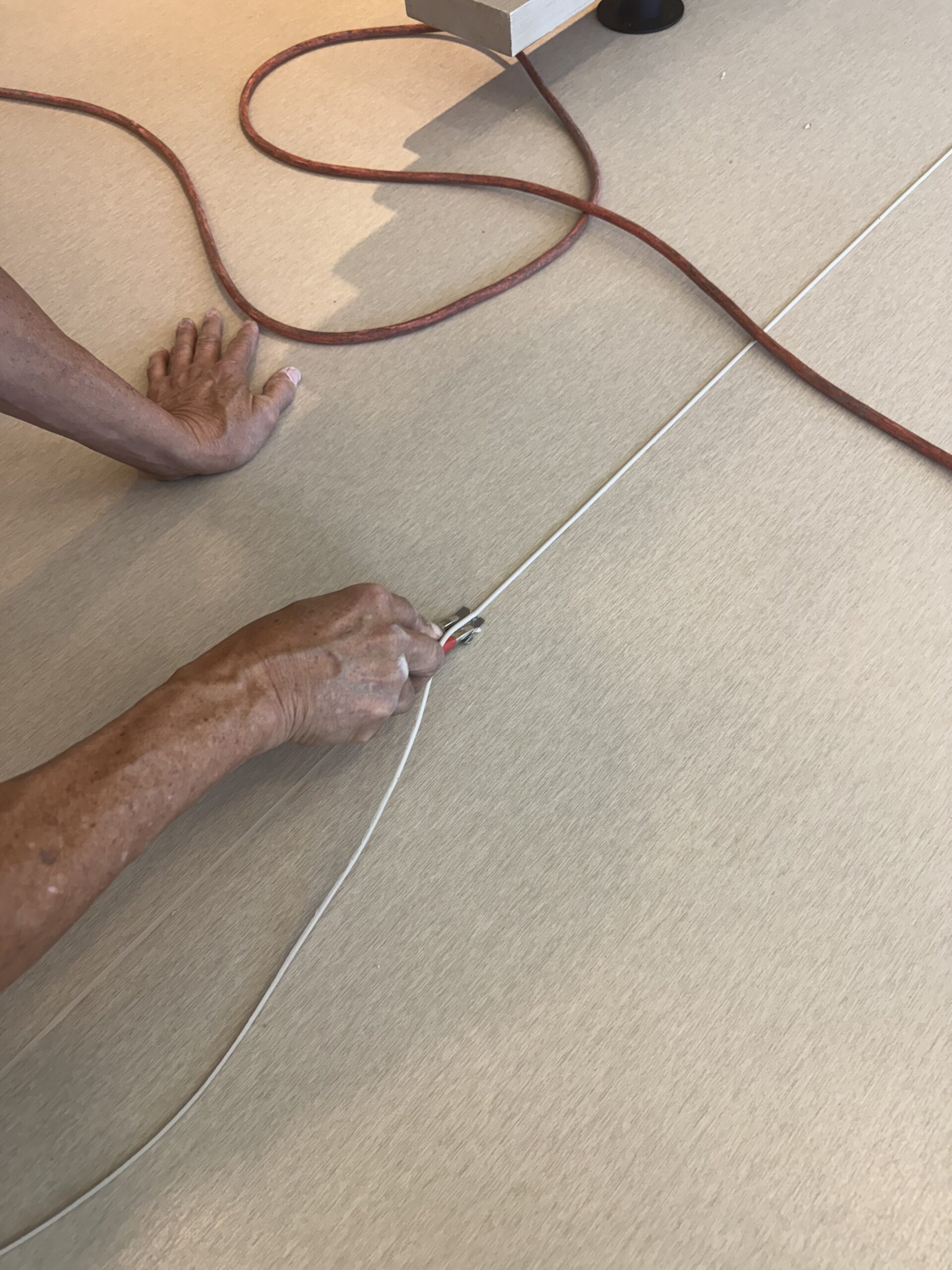 Installer trimming welded rod flush along a seam in commercial vinyl flooring