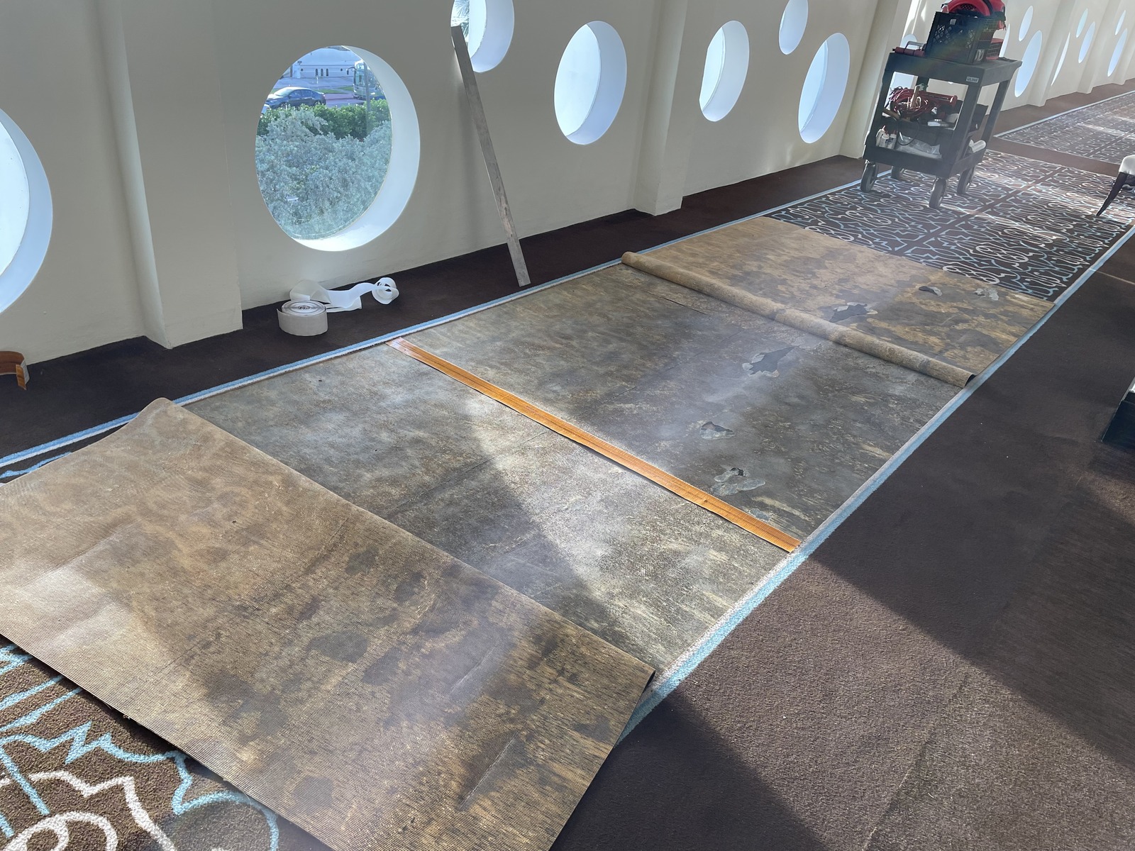 Worn carpet runner sections lifted along a commercial corridor with seam tape ready for repair in South Florida