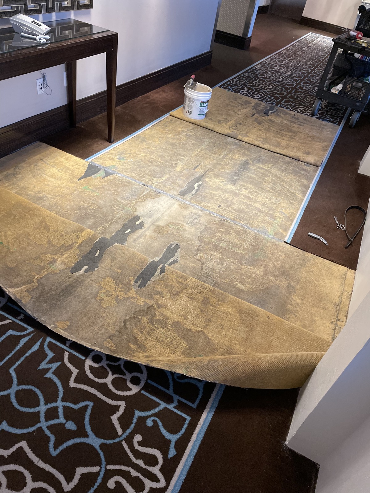 Hotel hallway carpet folded back at the seams with adhesive ready for a commercial carpet repair