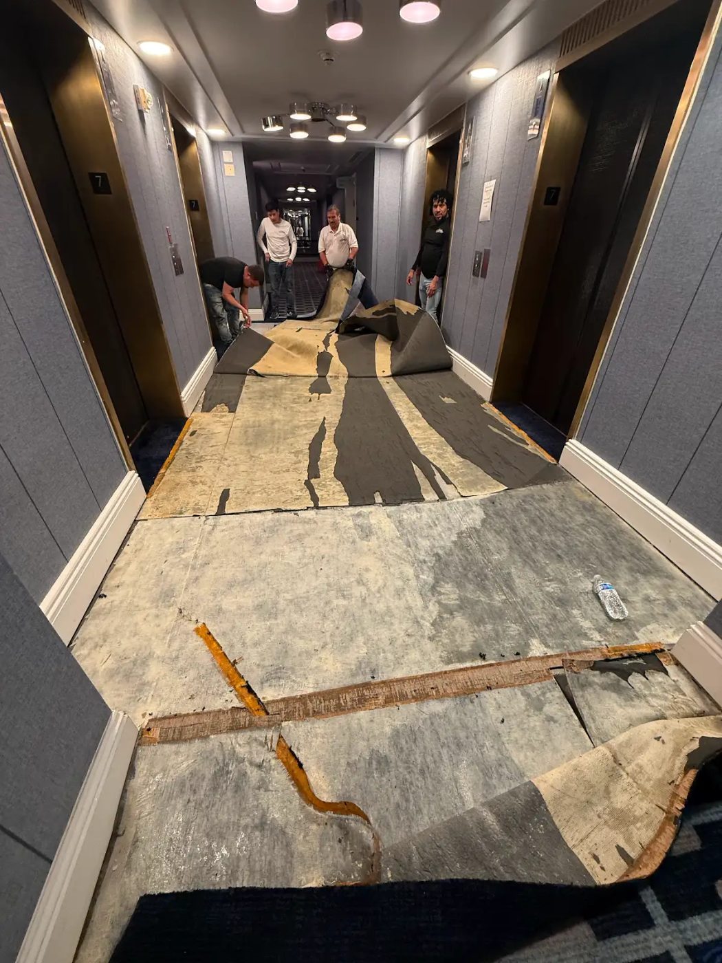 Old carpet lifted from a hotel corridor exposing the subfloor