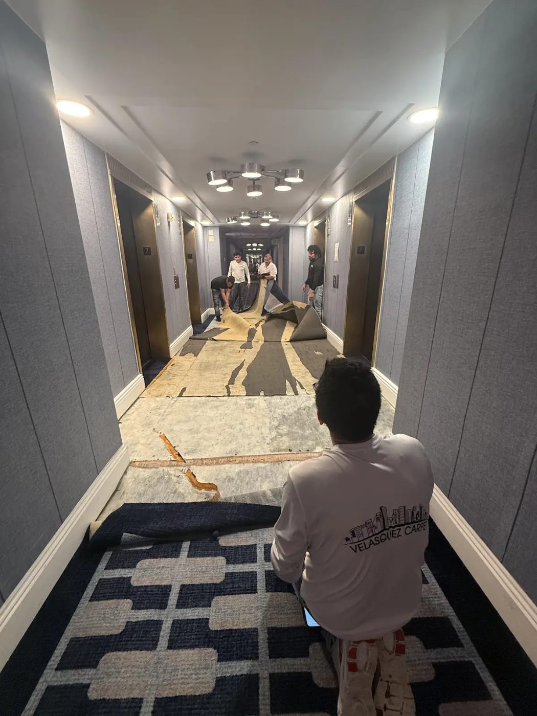 Velasquez Carpet crew pulling up old carpet in a hotel corridor in Miami